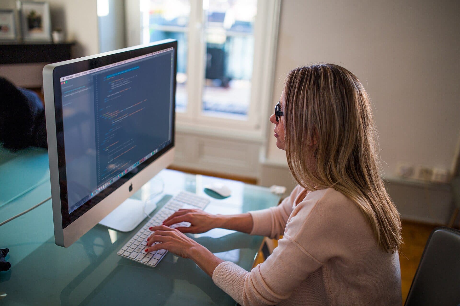 A woman working at a desktop computer in a bright office